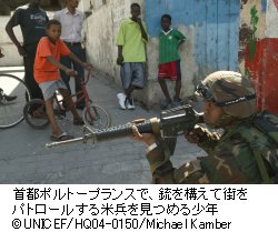 首都ポルトープランスで、銃を構えて街をパトロールする米兵を見つめる少年
