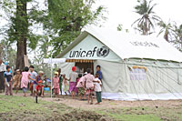 写真：ユニセフ提供の学校用テントの屋外で遊ぶ子どもたち