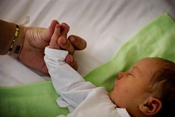母親に手を握られながら眠る赤ちゃん（セルビア）