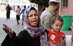 ガザ市にある病院の外で幼い息子を抱えながら診察を待つ女性。