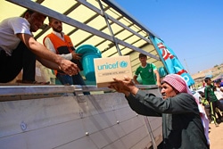 緊急支援物資の世帯向け・衛生用品の詰め合わせを受け取る避難している男性。（イラク）