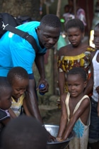 ユニセフのパートナー団体がエボラの感染を防ぐための正しい手洗いの方法を子どもたちに教える様子。（ギニア）