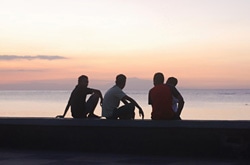 東ティモールの首都、ディリの海岸に座る少年たち。