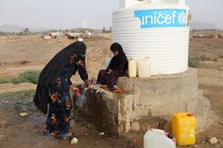 給水所で水を汲む国内避難民の女性と子ども（イエメン）。