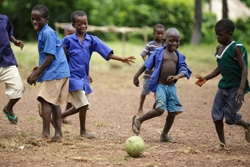 校庭でサッカーをして遊ぶ、シエラレオネの子どもたち。