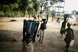 水でいっぱいのバケツを運ぶ子ども。