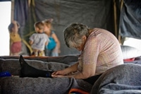 避難所のベッドの上でぐったりと座っている女性