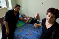 トビリシの病院で横たわる少年と親戚