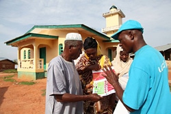 チラシを見せながらエボラ熱の予防法を住民に伝えるユニセフ職員