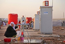 イラク・エルビル州のトランジットセンターにある水の供給所で水を汲む女性。