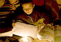 シャルフ一家では、ガザの自宅で子どもたちが、暗闇の中、ろうそくの灯りで読書をしています。