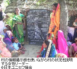 村の情報掲示板を使いながら村の状況を説明する女性リーダー