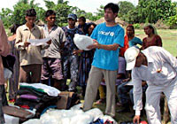 洪水被害を受けたパダナハ村の人々に、蚊帳や必須物資を配布するユニセフ職員。