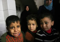 ガザ市内の崩壊した家の瓦礫の中を歩くパレスチナの男の子たち。