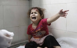 ガザ市にあるシファ（al-Shifa）病院で治療を行うスタッフを前に泣く女の子　（7月18日撮影）