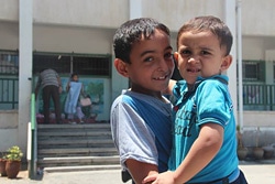 家族全員で学校へと避難してきた12歳のバデルくん（写真左：7月23日撮影）