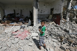 空爆で破壊された家の瓦礫の中を歩く男の子。（ガザ地区）