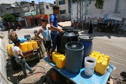 給水所でタンクに水を汲む子どもたち。（ガザ地区）