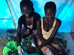 赤ちゃんの健康状態を確認するフローレンス助産師（左）と母親のクエイさん（右）