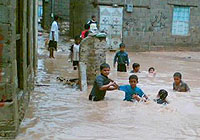 洪水の中、足をとられないように歩く子どもたち。