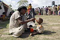 写真：重度の栄養不良の子どもに、スプーンで治療用のミルクを与える母親。