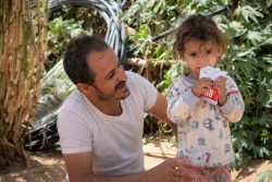 すぐに食べられる栄養治療食(RUTF)を口にする国内避難民の2歳の女の子と、それを見守る父親。(2020年3月撮影)