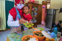 中部ジャワ州にある自宅で1歳のアブドラーちゃんのための食事を準備する母親。(インドネシア、2020年8月撮影)