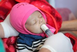 すぐに食べられる栄養治療食(RUTF)を口にする生後3カ月のサクルちゃん。今は回復しつつある。(2020年12月撮影)