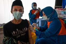 東ジャワ州にあるイスラム学校でCOVID-19ワクチンを受ける教師。(インドネシア、2021年3月23日撮影)