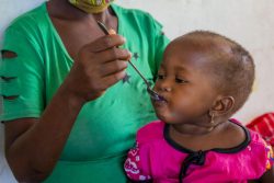 カボ・デルガド州のイボ島にある保健センターで、すぐに食べられる治療食(RUTF)を口にする中度の急性栄養不良の1歳のローザちゃん。(2020年12月撮影)