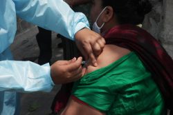 カトマンズにある予防接種センターで、COVID-19の予防接種をする医療従事者。(ネパール、2021年6月9日撮影)