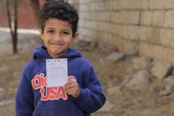 コレラの予防接種を受けた証明書を手に持つ7歳のファドルくん。(イエメン、2021年2月撮影)