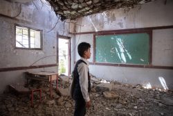 ハッジャ県にある爆撃で破壊された教室で、がれきの上に立つ12歳のアフメドくん。(イエメン、2021年3月撮影)
