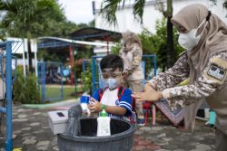 ジャカルタ東部の幼稚園の中に入る前に、先生と一緒に手を洗う5歳のジャガドちゃん。(インドネシア、2021年9月15日撮影) 