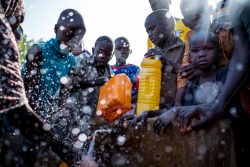 ナイジェリアのボルノ州マイドゥグリのダロリ・キャンプ内に設置された水道から、水容器に水を汲む国内避難民たち。