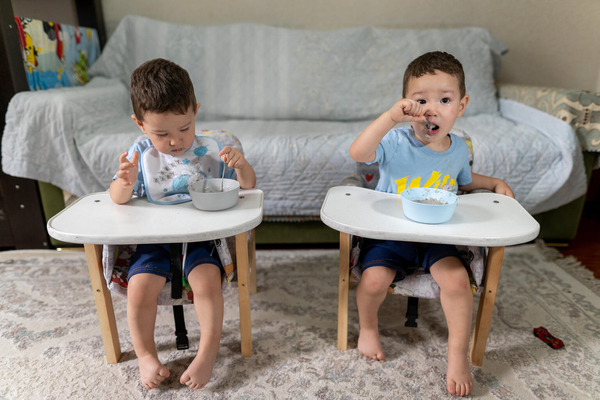ビシュケクの自宅で、好物のお粥を食べる双子の1歳のアデルちゃんとアリムちゃん兄弟。(キルギス、2021年8月28日撮影)