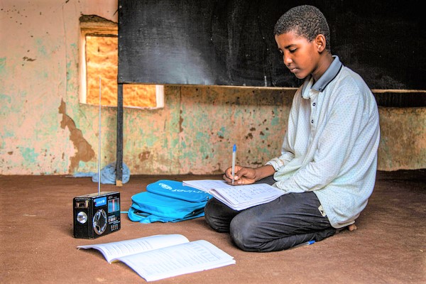 休校に対応するソーラー式ラジオを使い、授業を受ける12歳のモハメドくん。ユニセフが支援する遠隔教育プログラムのおかげで、中学校に入学することができた。(モーリタニア、2021年6月撮影)
