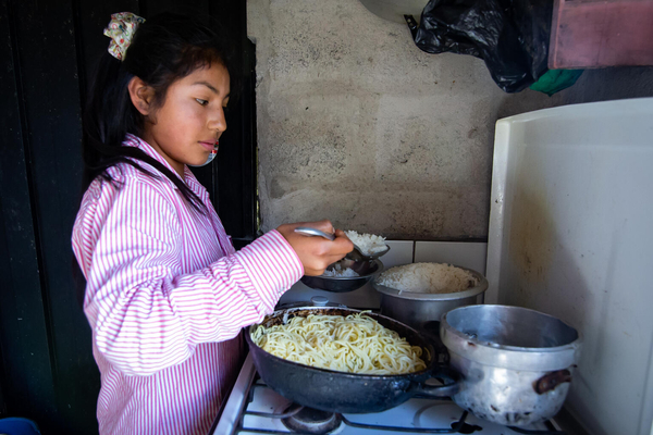 両親のために作ったお米とヌードルを昼食に準備する13歳のマルダリータさん。(エクアドル、2021年7月撮影)