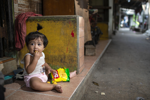 北ジャカルタのスラム街で、スナックを食べる生後11カ月のサルサビラちゃん。(インドネシア、2021年4月撮影)