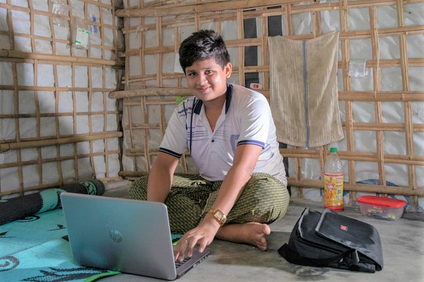 コックスバザールの難民キャンプの自宅で、パソコンを使ってコンピューターと英会話の授業を受ける15歳のロヒンギャ難民のムハマドくん。(バングラデシュ、2021年9月撮影)