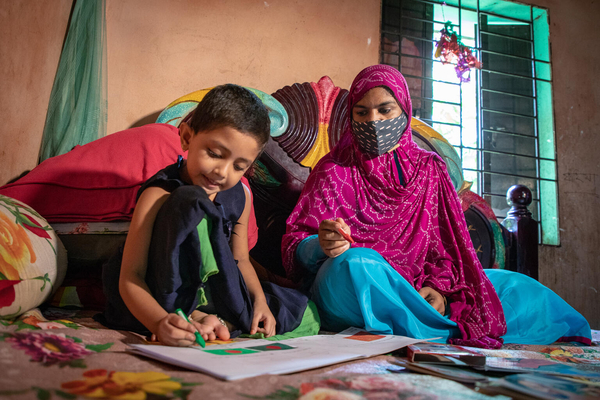 COVID-19の影響で未就学児向けの施設が一時的に閉鎖されたため、自宅を訪れたボランティアに教わりながら学習をすすめる4歳のスマイヤちゃん。(バングラデシュ、2021年8月撮影)