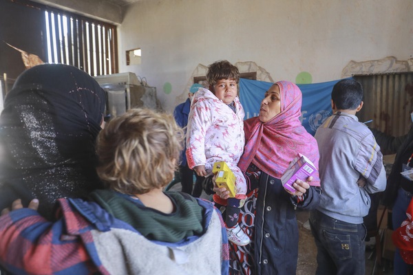 ハサカにある避難所のユニセフが支援する移動式クリニックで、栄養不良を防ぐための微量栄養パウダーを受け取った国内避難民の子どもと母親。(シリア、2022年1月28日撮影)