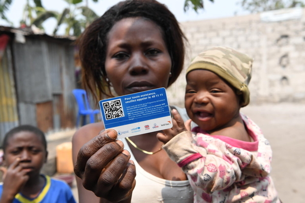 現金給付支援を受けられるカードを持つ、キンシャサの農村部に住む親子。COVID-19による経済的な影響で、子どもの食料確保が困難な家庭を対象に、現金給付支援が行われた。(コンゴ民主共和国、2021年8月撮影)