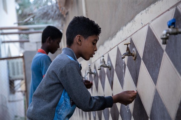 ハドラマウト州で、水道が使えるようになったことを喜ぶ8歳のアイマンくん。ディーゼル燃料を維持する資金が不足するイエメンで、ユニセフは水道システムの太陽光発電利用を支援している。(イエメン、2022年2月28日撮影)