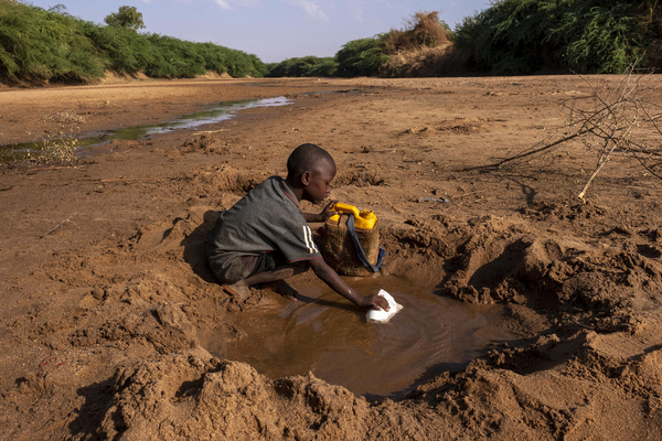 深刻な干ばつにより干上がった川から、わずかな水を集める男の子。 (ソマリア、2022年3月1日撮影)