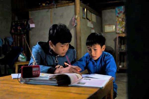ラオカイ省に住む、15歳のドゥオンさんと13歳のタインさん兄弟。COVID-19の影響で多くの同級生がスマートフォンやパソコンを使ってオンライン授業に参加する中、古いラジオで授業を録音して聴いている。 (ベトナム、2021年12月撮影)