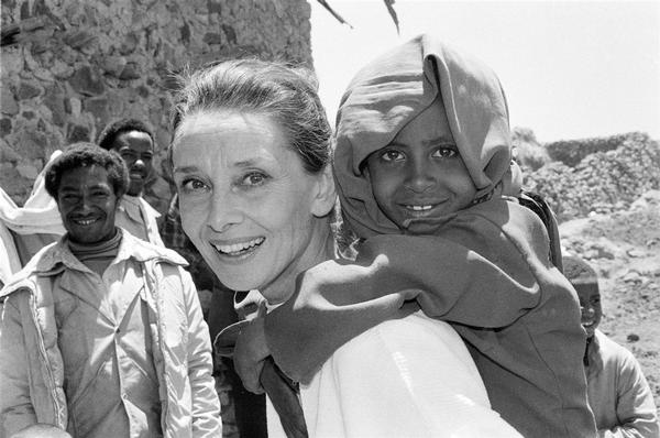 エチオピアで子どもと笑顔を見せるオードリー。ユニセフが支援する保健クリニックや栄養支援の現場、干ばつで捨てられたり親を失った子どもたちのための孤児院を訪問しました（1988）