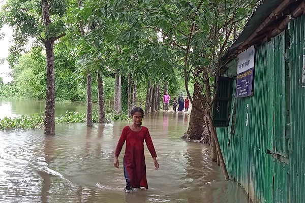 溢れた水の中を歩くエマさん。ユニセフが支援する学校に通っていたが、洪水によって水浸しになってしまった。(バングラデシュ、2022年5月17日撮影)
