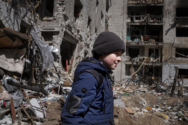 家族と住んでいたアパートの前を歩くボーダンさん(10歳)。度重なる爆撃によって破壊されてしまった。(ウクライナ、2022年4月15日撮影)