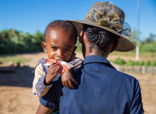 母親に抱かれながら、栄養治療食(RUTF)を食べる2歳の男の子。(マダガスカル、2022年3月撮影)